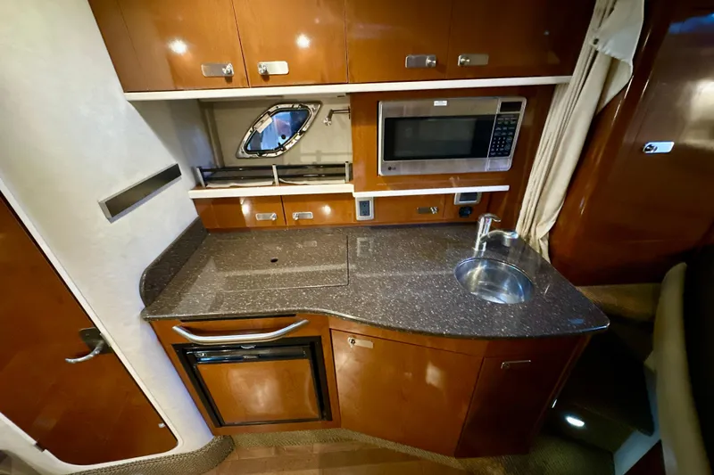 Slide: The Image of Luxurious 2012 Sea Ray 330 Sundancer yacht kitchen with microwave, sink, and wooden cabinetry. - 10
