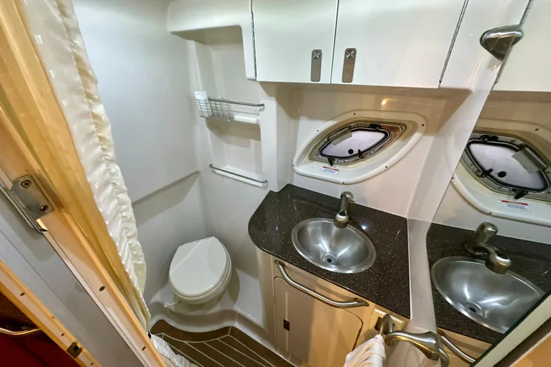 Slide: The Image of 2012 Sea Ray 330 Sundancer bathroom with sink, toilet, and porthole window. - 11