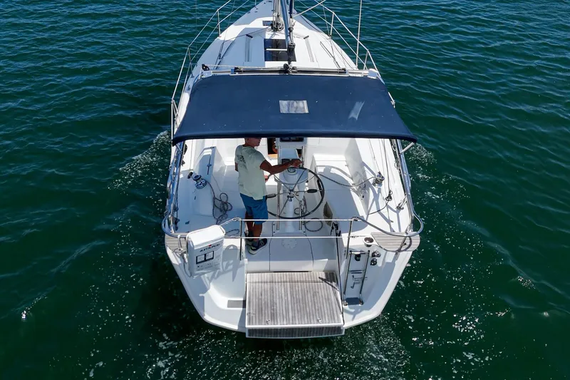 Slide: The Image of 2015 Hunter 33 sailboat on open water, viewed from above, with a person steering. - 2