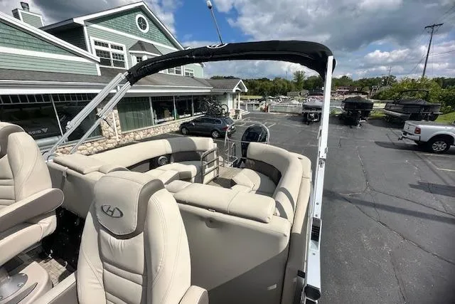 Slide: The Image of 2020 Harris Solstice 250 pontoon boat with beige seating, parked near a building under cloudy skies. - 37