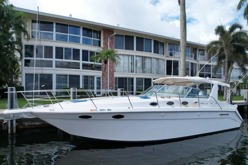 The Image of 1994 Sea Ray 370 Express Cruiser docked near modern waterfront building. - 0