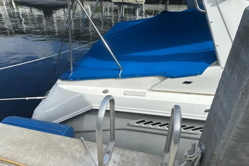 Slide: The Image of 1994 Sea Ray 370 Express Cruiser docked with blue cover, ladder visible. - 13