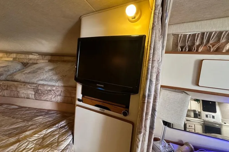 Slide: The Image of 1994 Sea Ray 370 Express Cruiser interior with TV, bed, and lamp. Cozy cabin setting. - 20