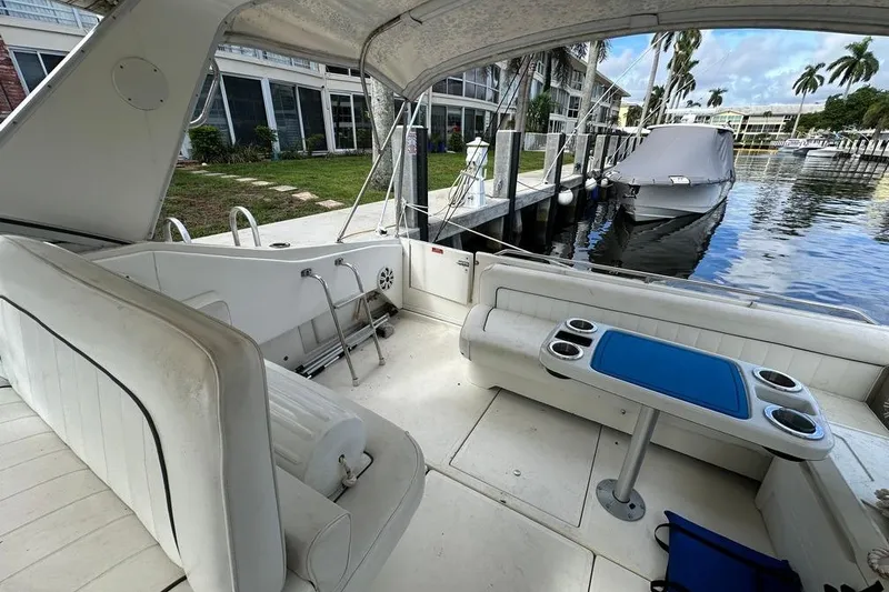 Slide: The Image of 1994 Sea Ray 370 Express Cruiser interior with seating and table, docked by waterfront. - 27