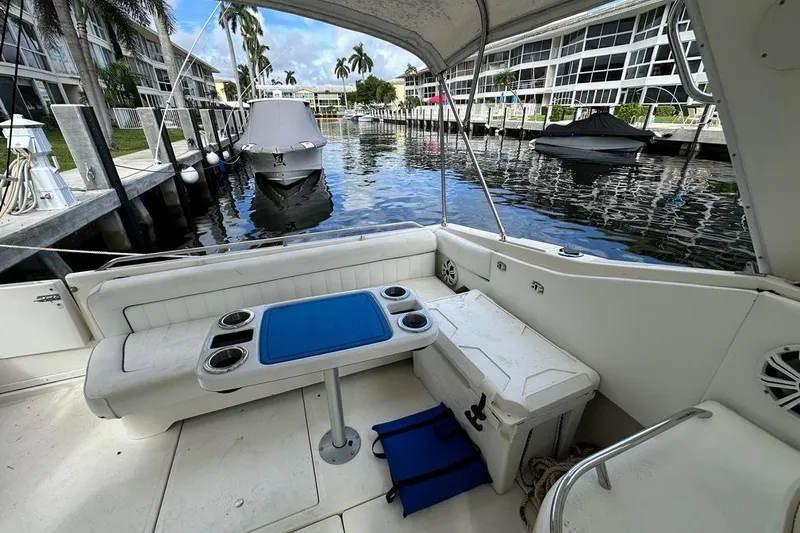 Slide: The Image of 1994 Sea Ray 370 Express Cruiser interior with seating and table, docked by waterfront homes. - 28