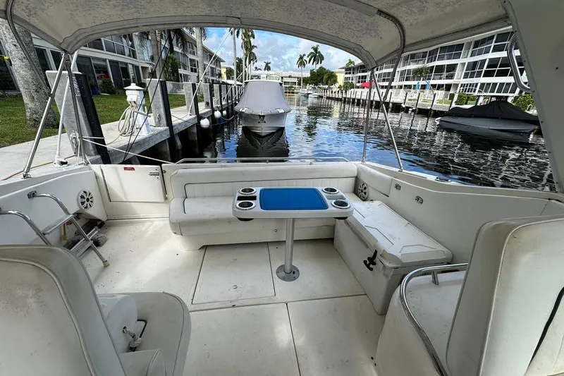 Slide: The Image of 1994 Sea Ray 370 Express Cruiser interior with seating and table, docked by waterfront. - 29