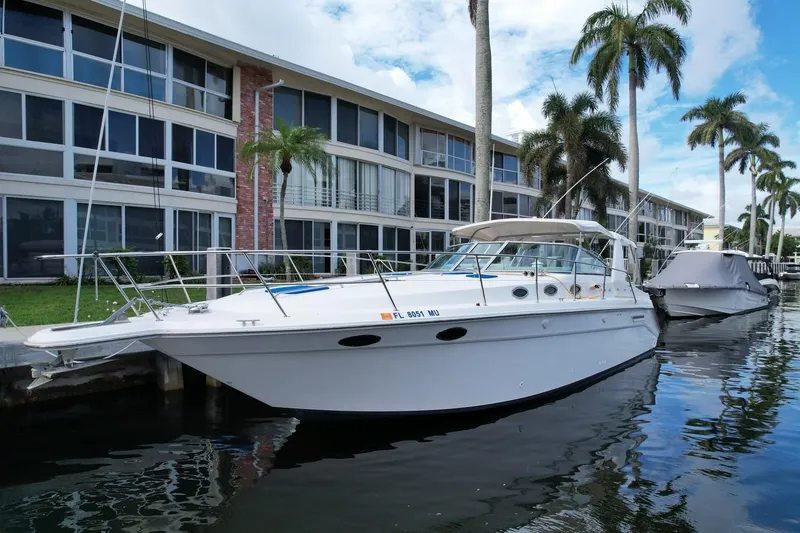 Slide: The Image of 1994 Sea Ray 370 Express Cruiser docked by waterfront apartments with palm trees. - 35