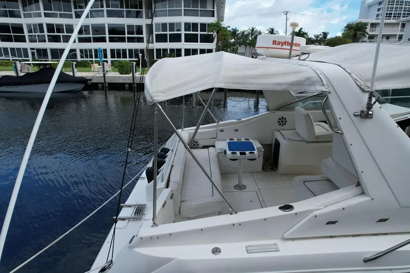 Slide: The Image of 1994 Sea Ray 370 Express Cruiser docked near waterfront buildings, featuring a covered seating area. - 48
