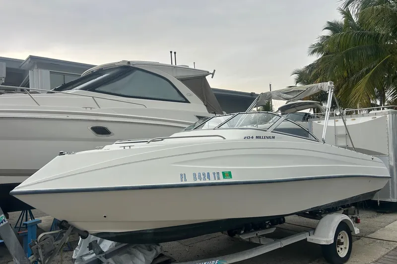 The Image of 2001 Sea Fox 204 Millenium boat on trailer, parked beside another vessel, with palm trees in background. - 1