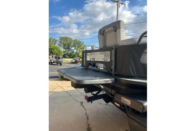 Slide: The Image of 2023 Sea Doo Switch rear view with seating, parked outdoors under a blue sky. - 2