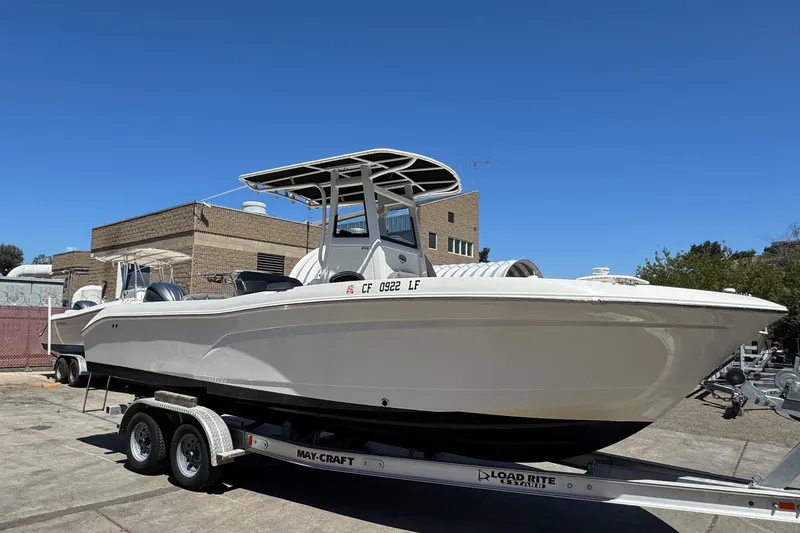 Slide: The Image of 2023 NauticStar 242L Offshore boat on trailer, parked outdoors under clear blue sky. - 12