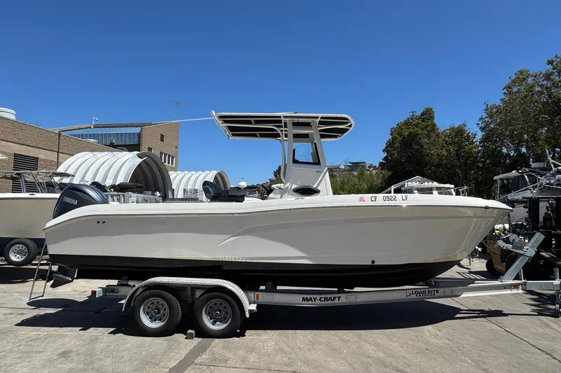 Slide: The Image of 2023 NauticStar 242L Offshore boat on trailer, parked outdoors under clear blue sky. - 13