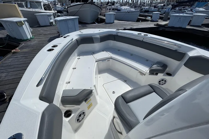 Slide: The Image of 2023 NauticStar 242L Offshore boat interior with seating and speakers at a marina. - 18