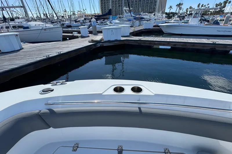 Slide: The Image of 2023 NauticStar 242L Offshore boat docked at marina with sailboats in background. - 32