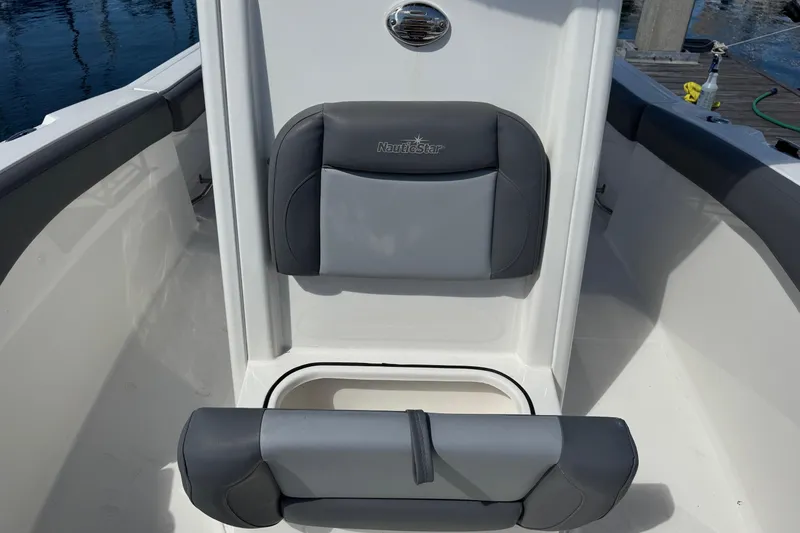 Slide: The Image of 2023 NauticStar 242L Offshore boat seating with gray cushions and storage compartment. - 33
