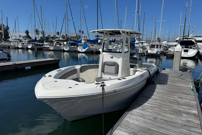 Slide: The Image of 2023 NauticStar 242L Offshore boat docked at a marina with sailboats in the background. - 51