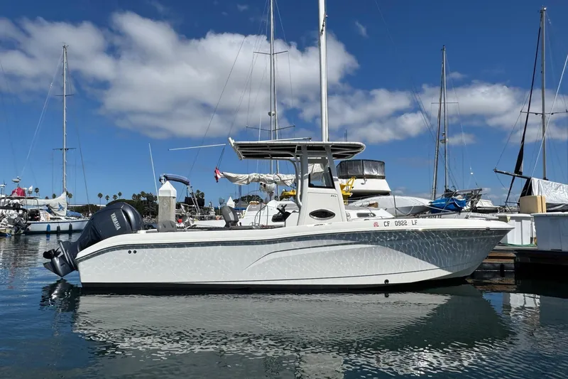 Slide: The Image of 2023 NauticStar 242L Offshore boat docked in a marina under a clear blue sky. - 54