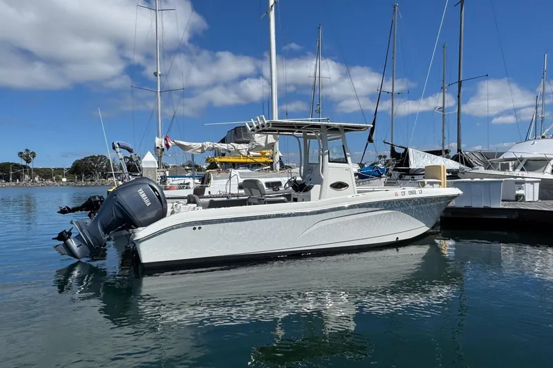 Slide: The Image of 2023 NauticStar 242L Offshore boat docked in a marina under a clear blue sky. - 55