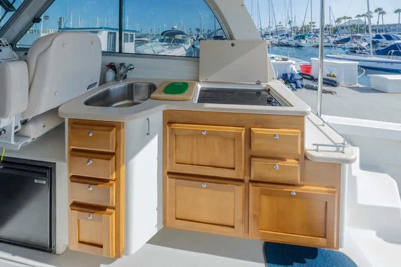 Slide: The Image of 2008 Back Cove 33 yacht kitchen with sink, stove, and wooden cabinets in marina setting. - 11