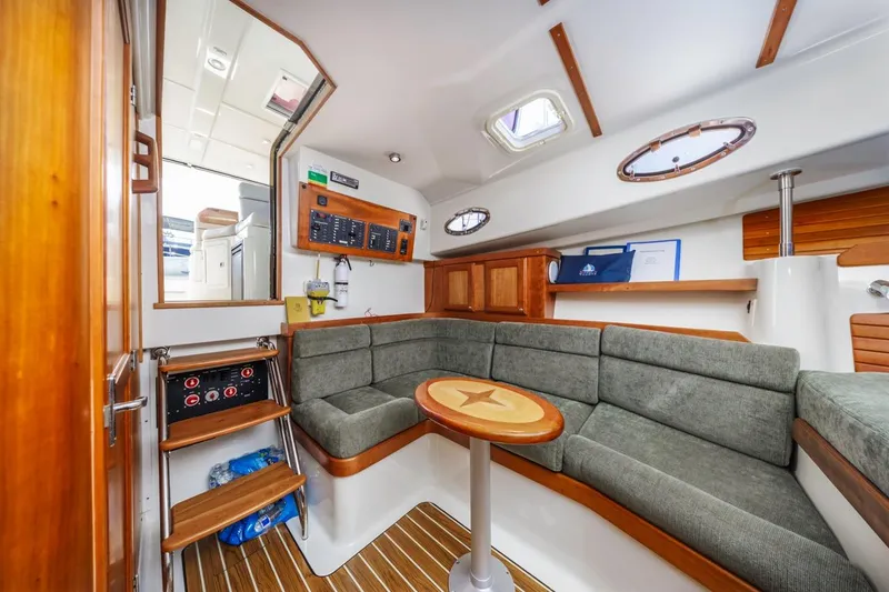 Slide: The Image of 2008 Back Cove 33 yacht interior with cozy seating, wooden accents, and control panel. - 22
