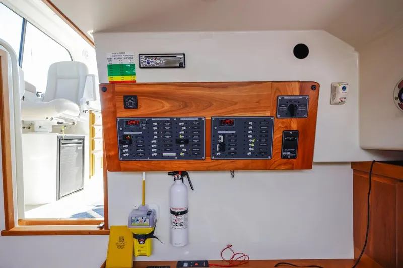 Slide: The Image of Electrical panel inside a 2008 Back Cove 33 boat, featuring control switches and a fire extinguisher. - 23
