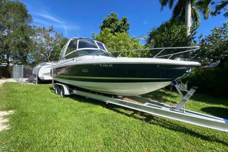 Slide: The Image of 2005 Formula 280 Sun Sport boat on trailer, parked on grass, surrounded by trees. - 4