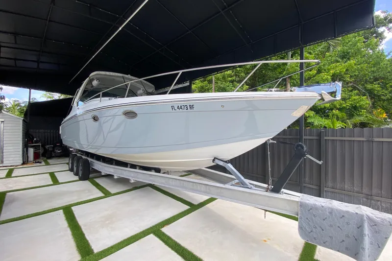 Slide: The Image of 2005 Formula 330 Sun Sport boat on trailer under canopy, surrounded by greenery. - 2