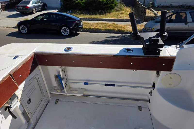 Slide: The Image of 2003 Boston Whaler 255 Conquest boat interior with rod holders and storage compartment. - 13