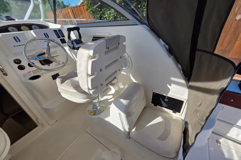 Slide: The Image of 2003 Boston Whaler 255 Conquest helm with steering wheel and controls, featuring white seating. - 17