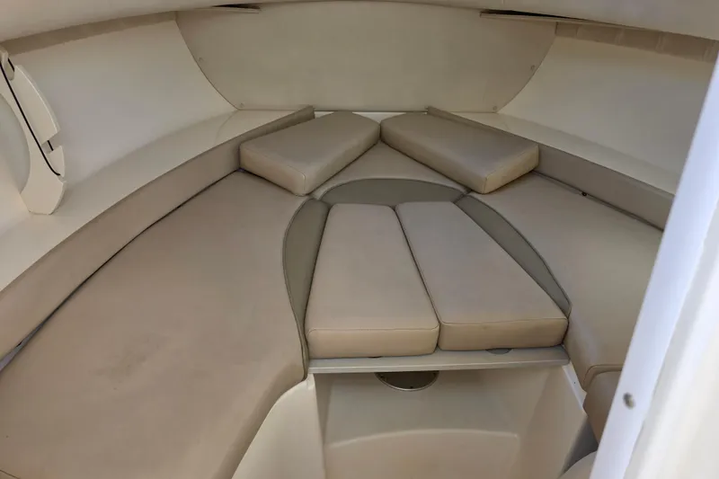 Slide: The Image of 2003 Boston Whaler 255 Conquest cabin interior with beige cushions and seating area. - 28