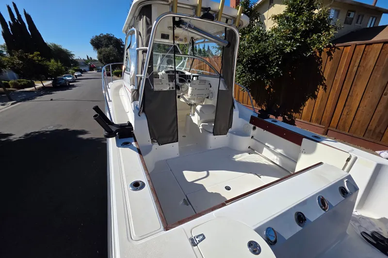 Slide: The Image of 2003 Boston Whaler 255 Conquest boat, docked on a sunny residential street. - 5
