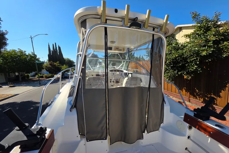Slide: The Image of 2003 Boston Whaler 255 Conquest boat with enclosed cockpit, parked on a residential street. - 6