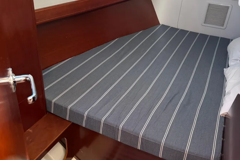 Slide: The Image of Cozy cabin bed in 2002 Beneteau Oceanis 393 sailboat, featuring striped bedding. - 12