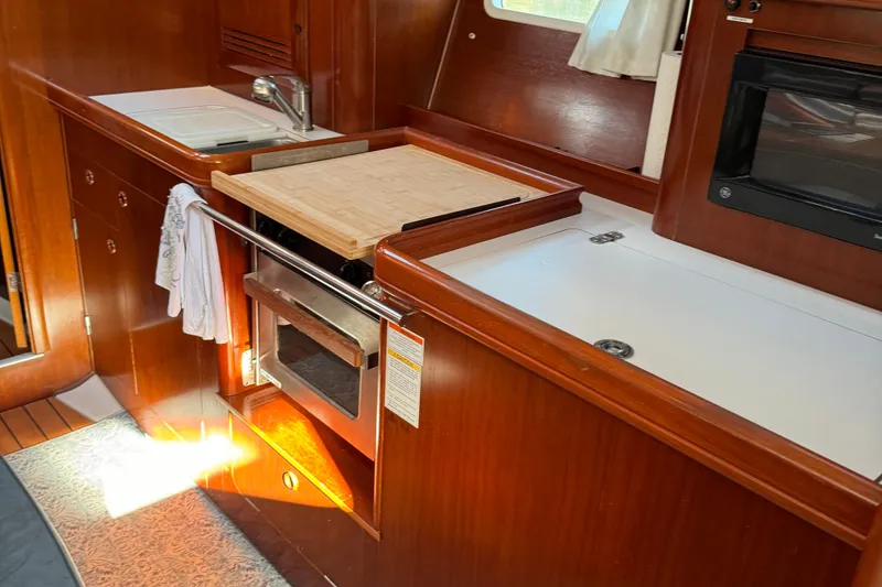 Slide: The Image of 2002 Beneteau Oceanis 393 yacht kitchen with wood cabinetry and modern appliances. - 13