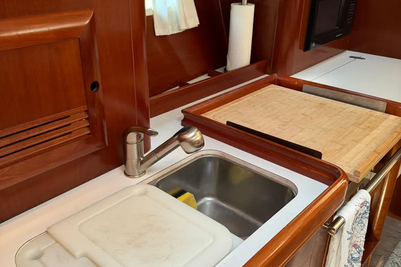 Slide: The Image of Galley kitchen in 2002 Beneteau Oceanis 393 sailboat with sink and cutting board. - 14