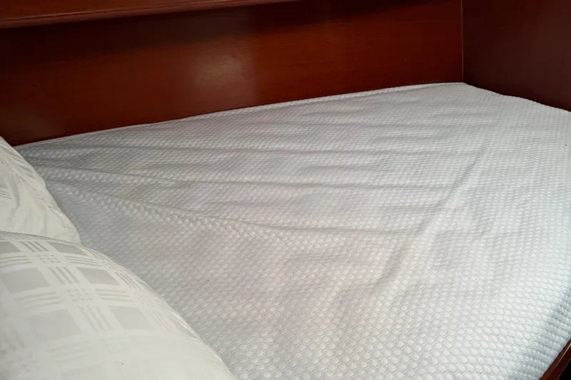 Slide: The Image of Cozy cabin bed in 2002 Beneteau Oceanis 393 sailboat, featuring white bedding. - 15