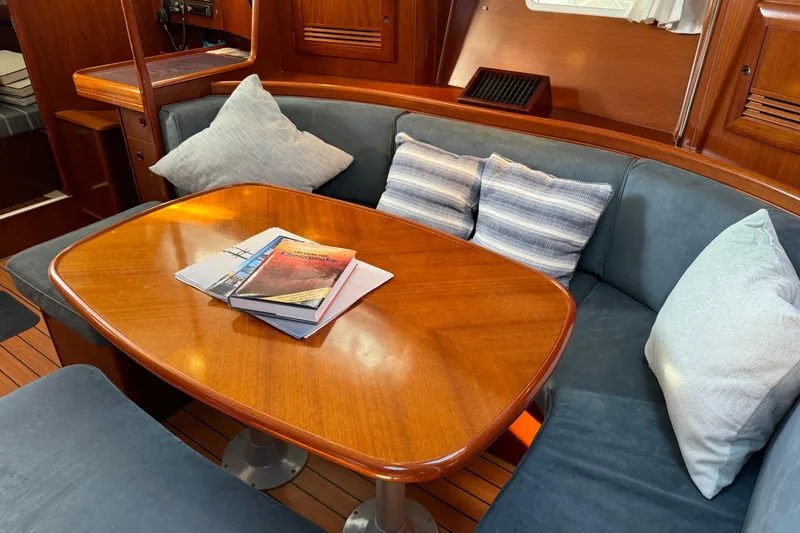 Slide: The Image of Interior of 2002 Beneteau Oceanis 393 yacht with cozy seating and wooden table. - 2