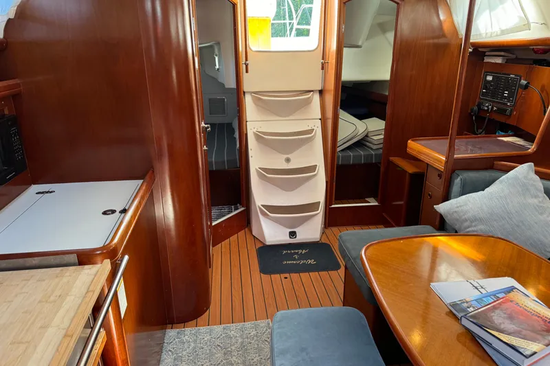 Slide: The Image of Interior of 2002 Beneteau Oceanis 393 sailboat, featuring wood finishes and cozy seating area. - 8