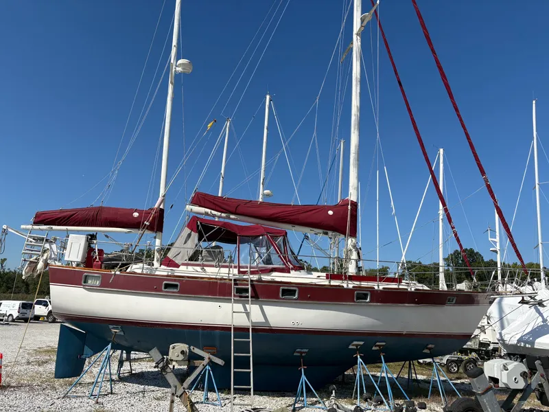 The Image of 1984 Irwin 41 sailboat on stands, red and white hull, clear blue sky background. - 0