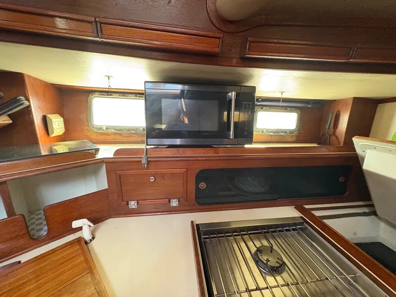 Slide: The Image of 1984 Irwin 41 yacht kitchen interior with microwave, stove, and wooden cabinetry. - 13
