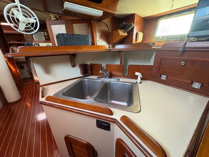 Slide: The Image of 1984 Irwin 41 yacht kitchen with dual sinks, wooden cabinetry, and a fan. - 15