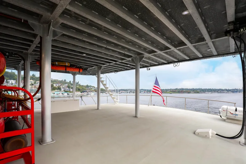 Slide: The Image of Spacious deck of 2007 MetalCraft Catamaran with American flag, overlooking serene waters. - 9