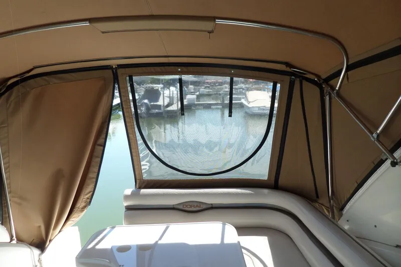 Slide: The Image of Interior view of a 2003 Doral 280 SE boat with tan canopy and marina backdrop. - 15