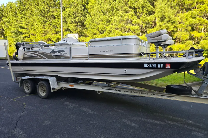 The Image of 2003 Hurricane 226R boat on trailer, parked on asphalt with trees in background. - 1