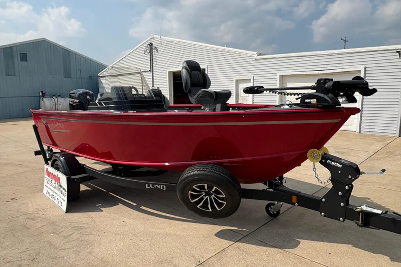 Slide: The Image of 2026 Lund 1800 Explorer SS boat in red on a trailer, parked outside a building. - 8