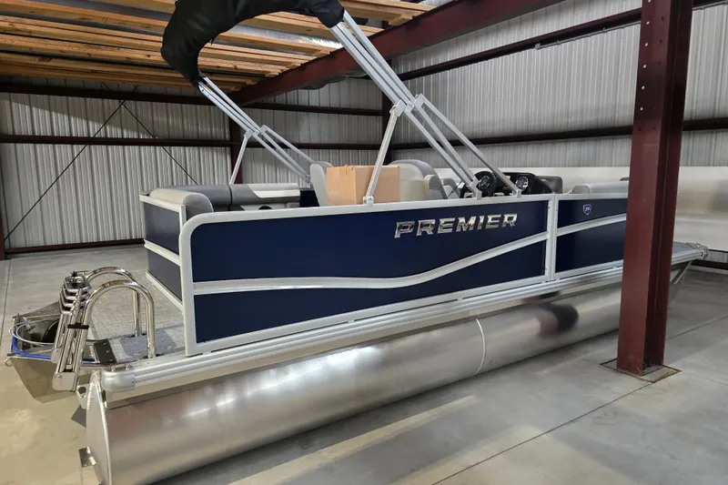 Slide: The Image of 2026 Premier 200 Sunscape pontoon boat parked beside a large green building. - 4