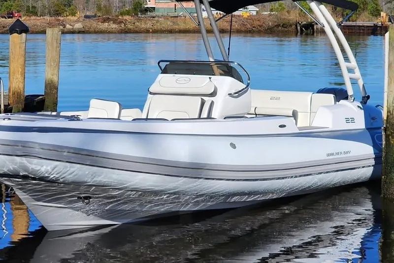 Slide: The Image of 2023 Walker Bay WB 22 boat docked on calm water, showcasing sleek design and modern features. - 2