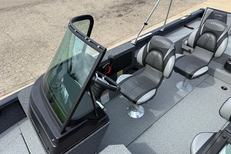 Slide: The Image of 2026 Lund 2075 Impact XS boat interior with steering console and two cushioned seats. - 16