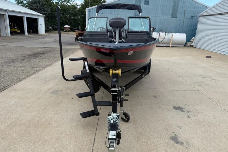 Slide: The Image of 2026 Lund 2075 Impact XS boat on trailer, parked in industrial area. - 2