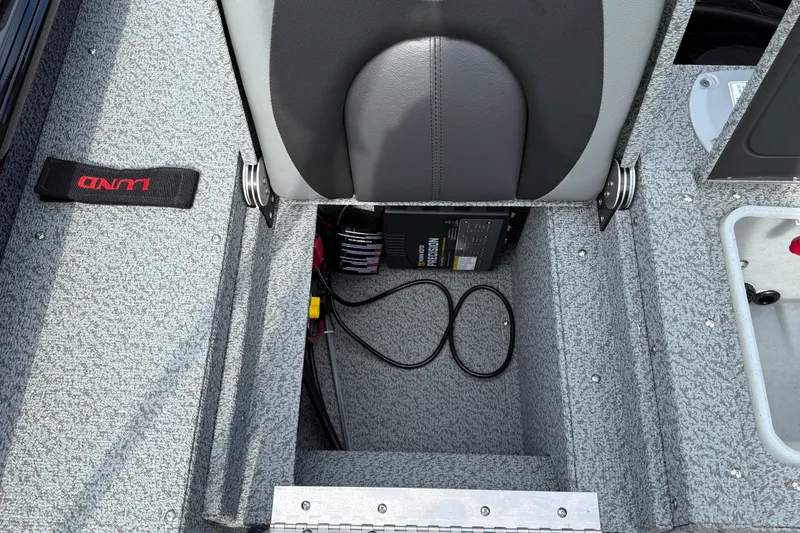 Slide: The Image of 2026 Lund 2075 Impact XS boat interior with storage compartment and battery charger. - 28